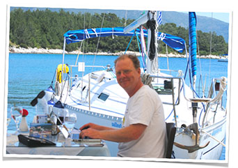 Photo of Tony Goodrow using his laptop next to a boat he wishes he owned